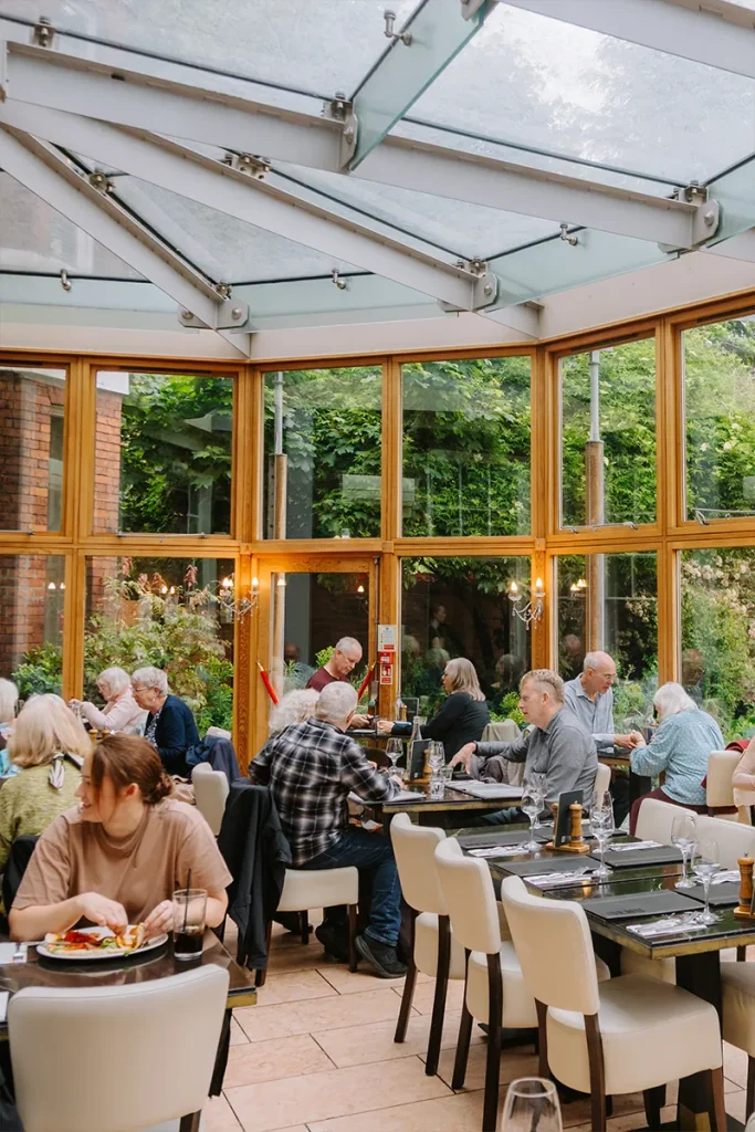 Guests dining in the glass conservatory overlooking the gardens at La Vecchia Scuola York